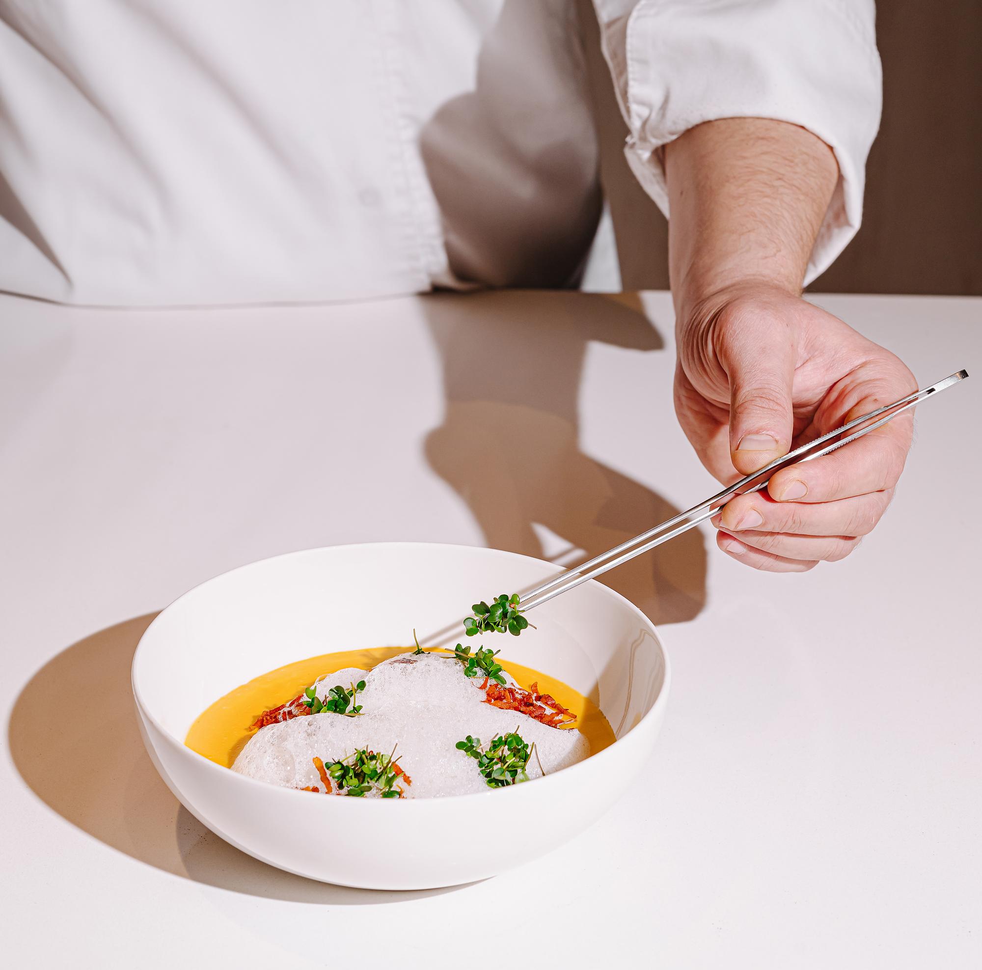 Chef arranging plated dish in calm kitchen